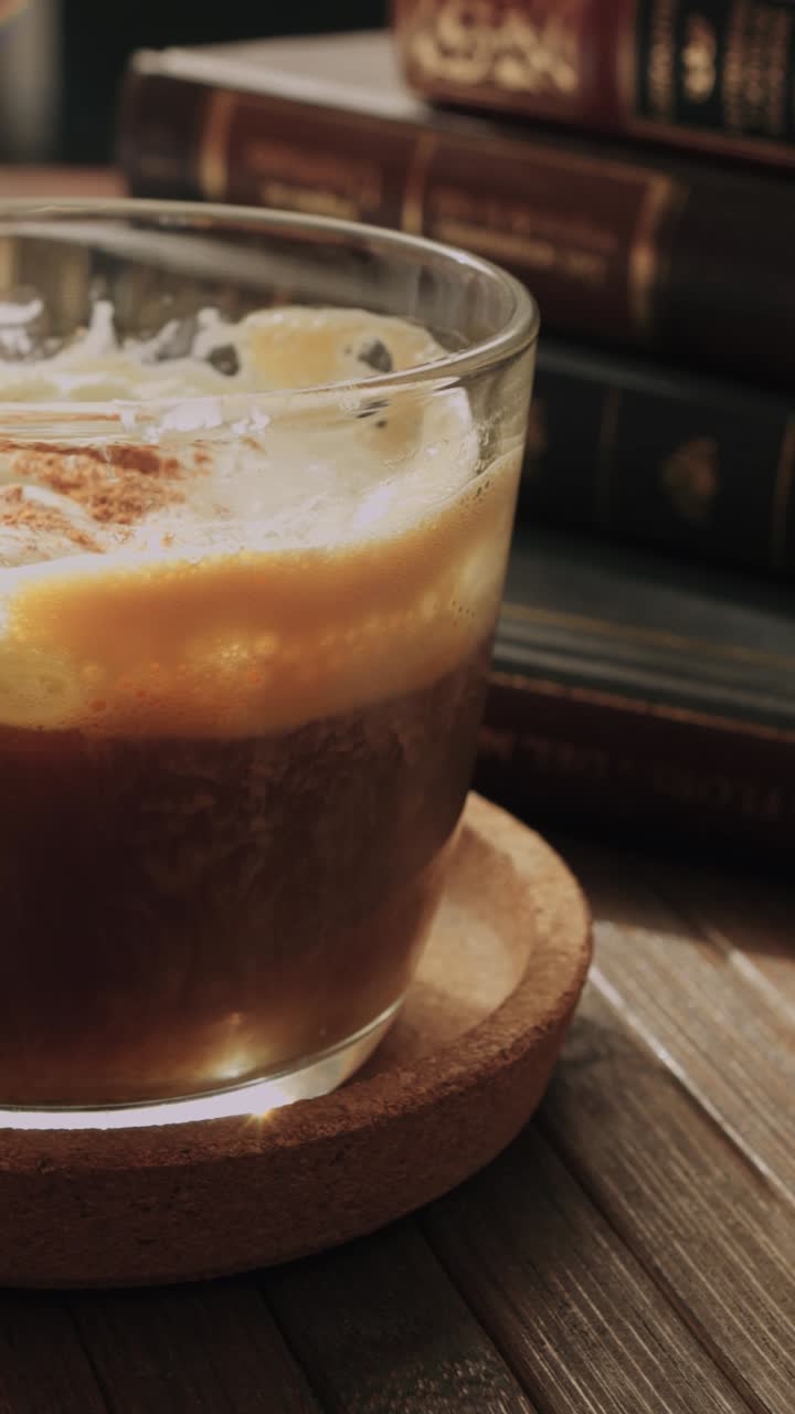 Caffè freddo con cannella e pila di libri vintage
