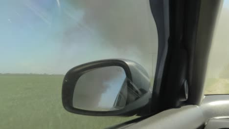 inside car driving towards black smoke fire in the distance, handheld