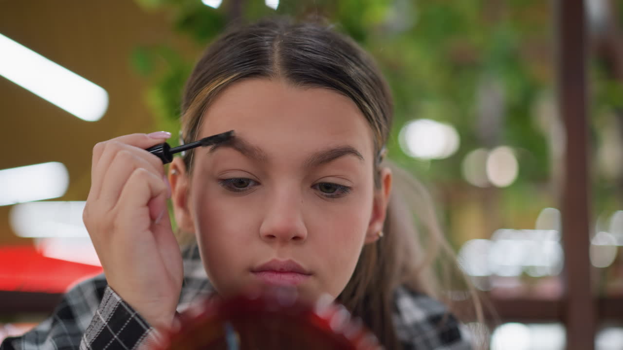 vista de primer plano de una mujer aplicando maquillaje en su ceja usando un pincel para cejas, centrarse en la aplicación precisa del producto cosmético para dar forma y arreglar las cejas, con un fondo borroso
