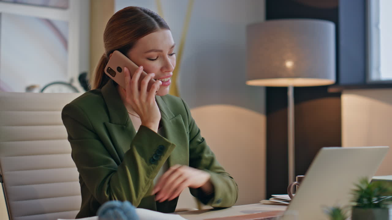 Nærbillede af glad medarbejder, der taler i telefon på aftenkontoret. Kvinde i telefonopkald.