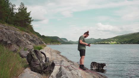 european man fishing by the lake with alaskan malamute dog