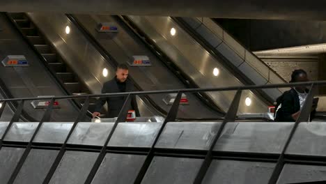 people riding escalators in a london underground station