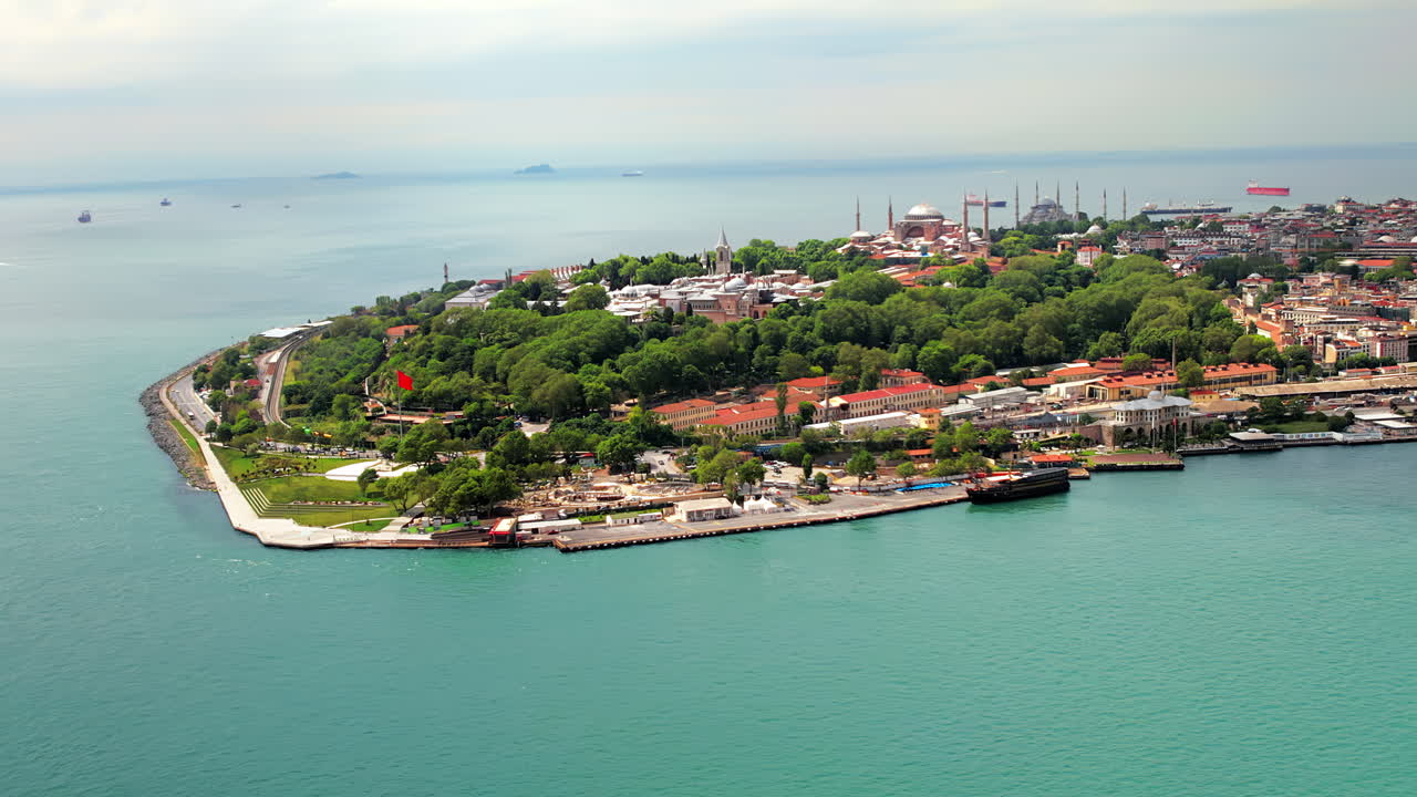 Aerial drone view of Istanbul at sunset, Turkey. Sultanahmet district with greenery and Hagia Sophia in the distance, Bosporus strait with floating ships
