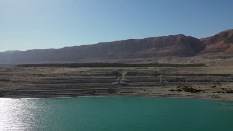 Diapositiva-Lateral-Aérea-Disparada-Sobre-Agua-Verde-En-El-Mar-Muerto-De-Israel,-Día-Soleado