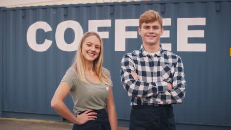 portrait of male and female interns at freight haulage business standing by shipping container