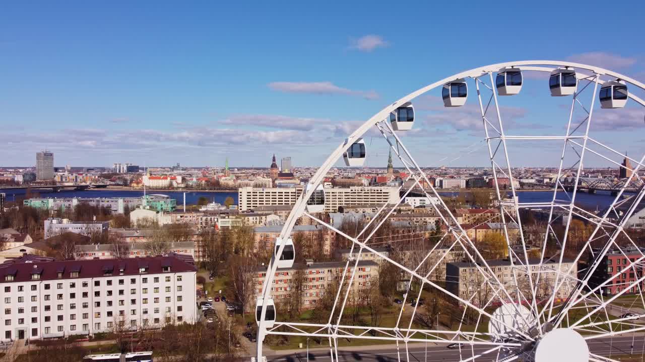 White Ferris Wheel with cityscape of Riga, Latvia in the background, showcasing recreational attraction in big capital city