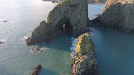 drone still of big sea stack with cave and blue seas copper coast waterford ireland beauty spot