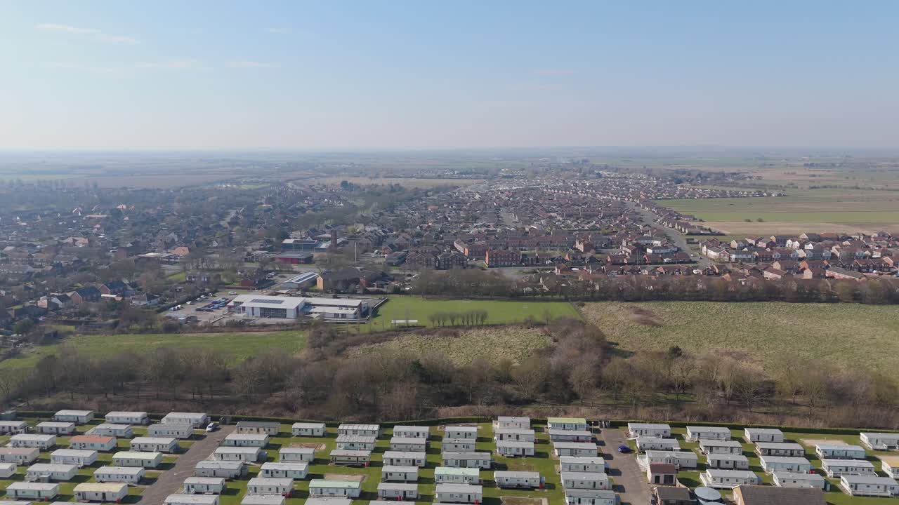 Warm light bathing the coastal holiday town of Skegness in Lincolnshire. Aerial views of hotels houses, theme parks and static holiday homes. Destination and tourist vacation, summer evening scene
