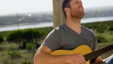 front view of caucasian man singing and playing guitar with eyes closed 4k