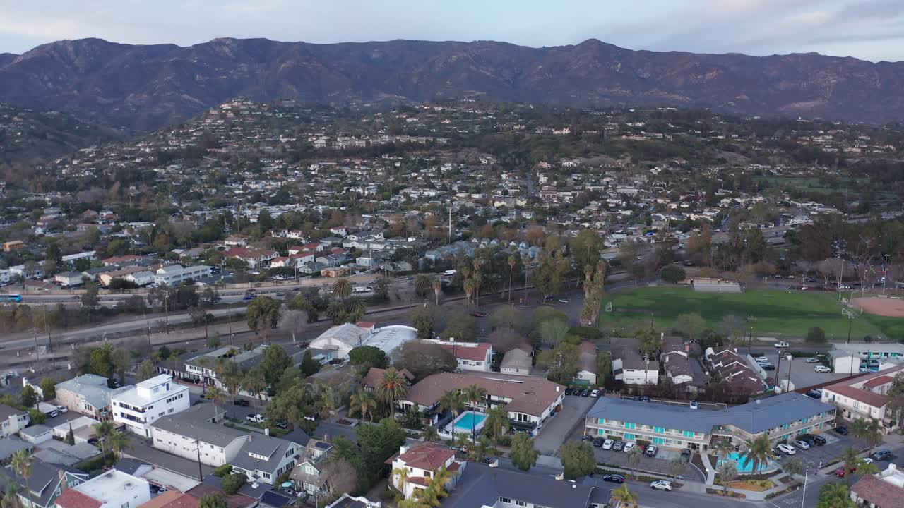 Wide descending aerial shot of Highway 101 running through Santa Barbara, California at sunset. 4K