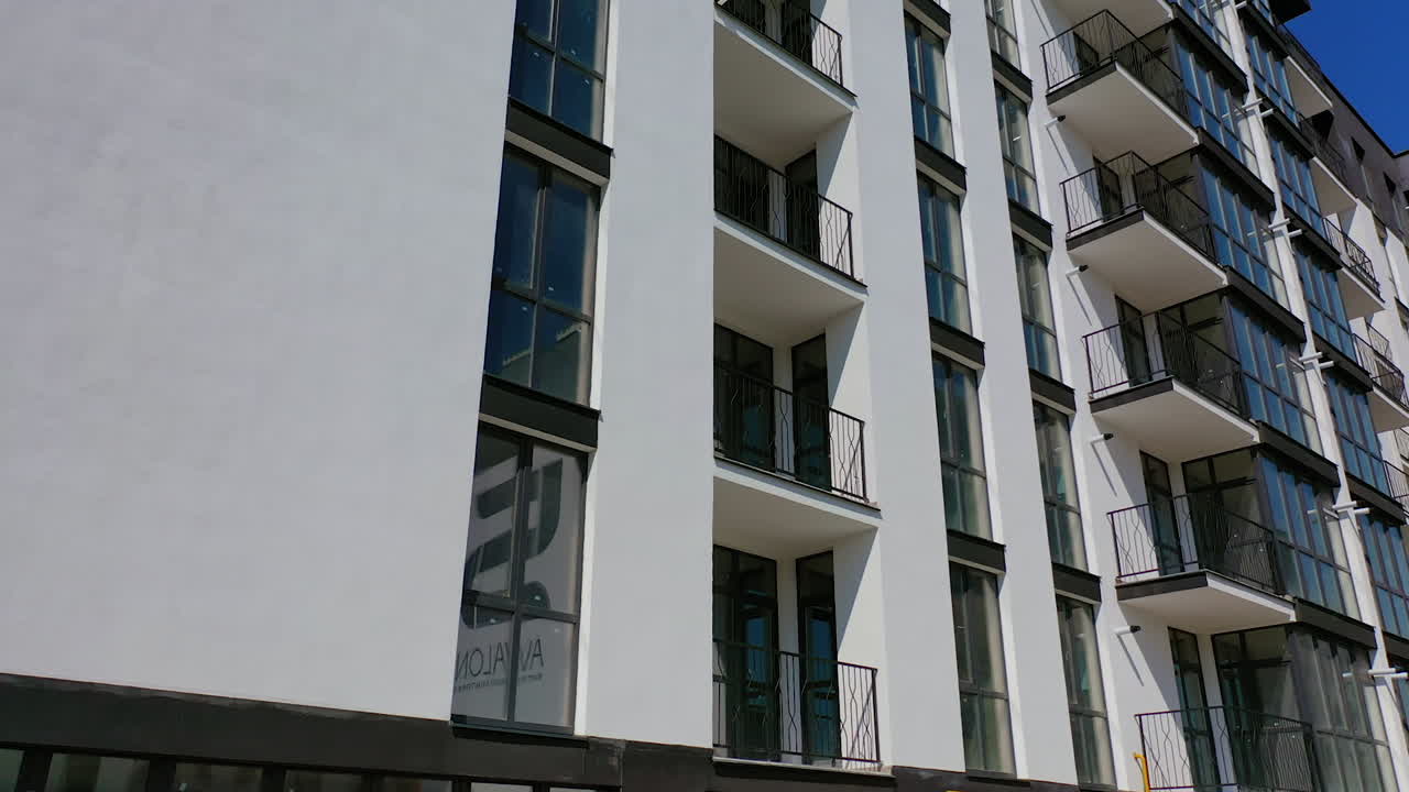 Facade of a newly built apartment building. Modern high-raised building with glass windows and balconies. Residential architecture.