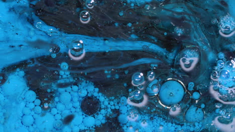 abstract art background of swirling blue and black paint with bubbles reacting and swirling