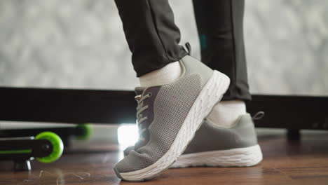 woman legs step on treadmill surface at home closeup. active lady in stylish sports shoes prepares to exercise on trainer machine in gym. jogging fan