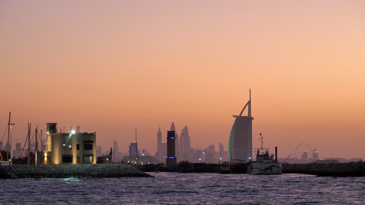 Skyline de la Marina de Dubaï et du Burj Al Arab après le coucher du soleil, ciel aux reflets orangés