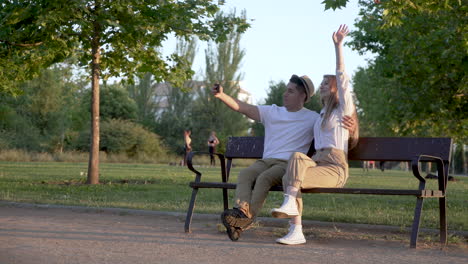 young couple taking a selfie on their mobile sitting in the park. latin man and caucasian woman