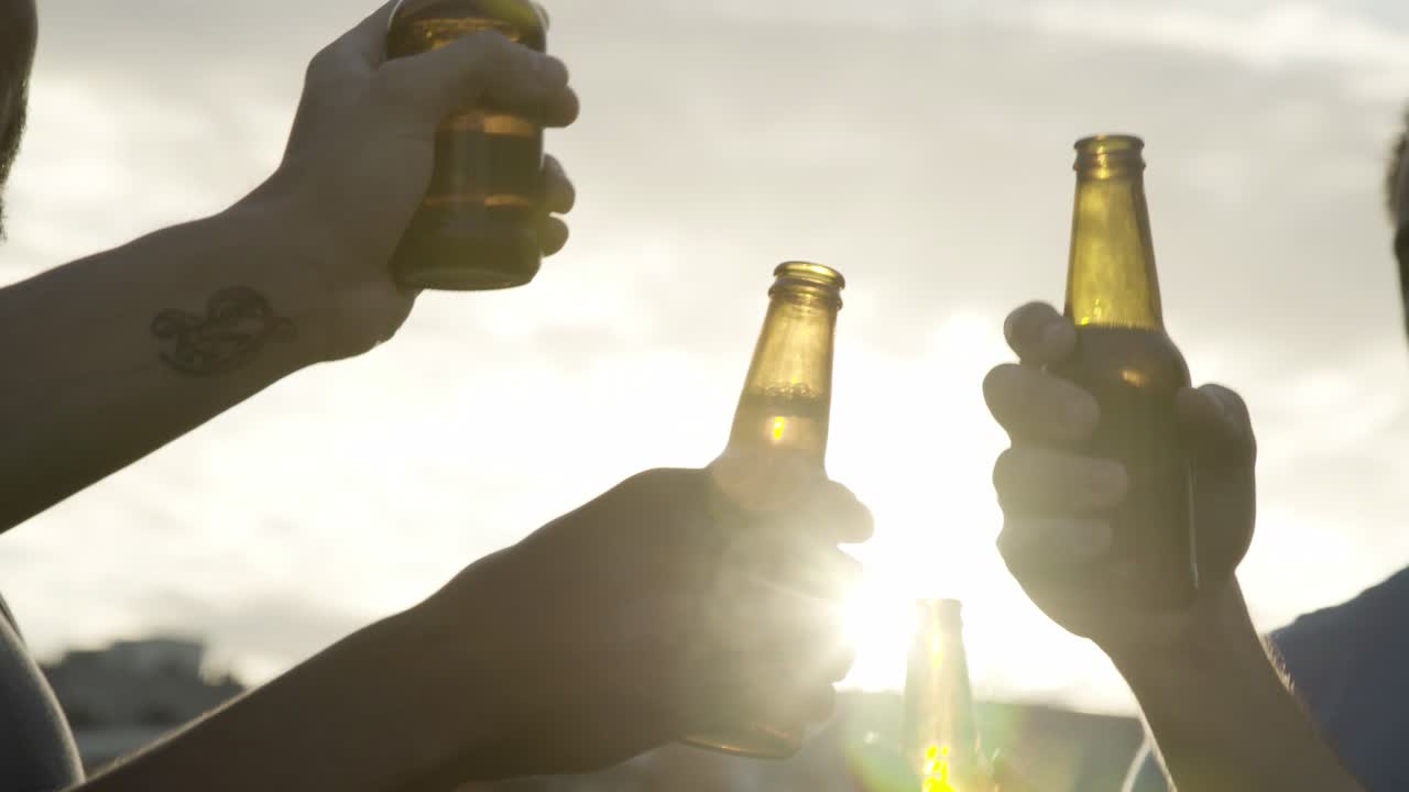 hombres jóvenes sonrientes bailando con botellas de cerveza