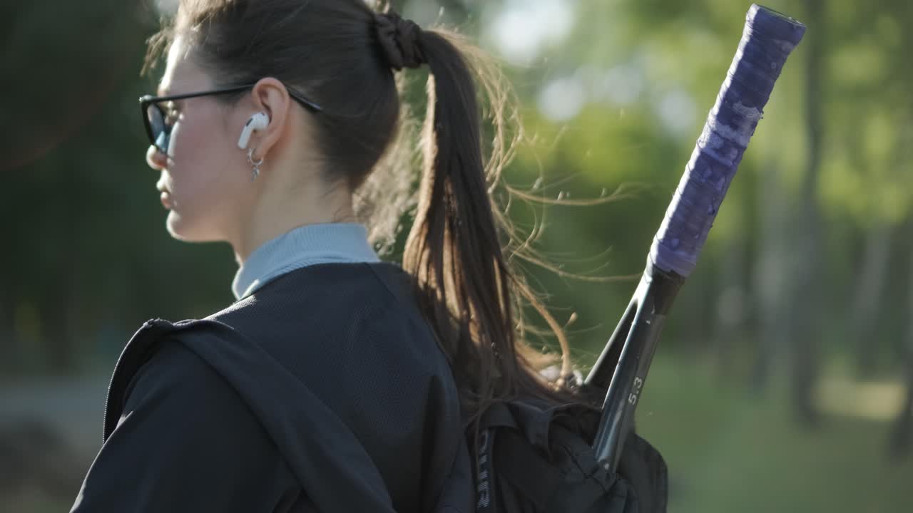 여자 테니스 선수 가 기어 가방 과 라켓 을 들고 고 있다