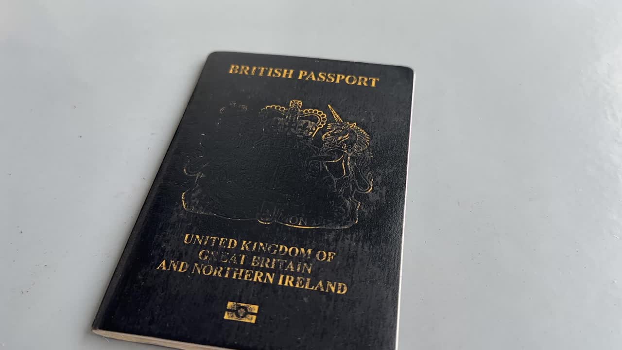 Detailní záběr z pohledu první osoby na muže držícího britský pas, cestovní identifikační dokument Spojeného království ve špatném stavu