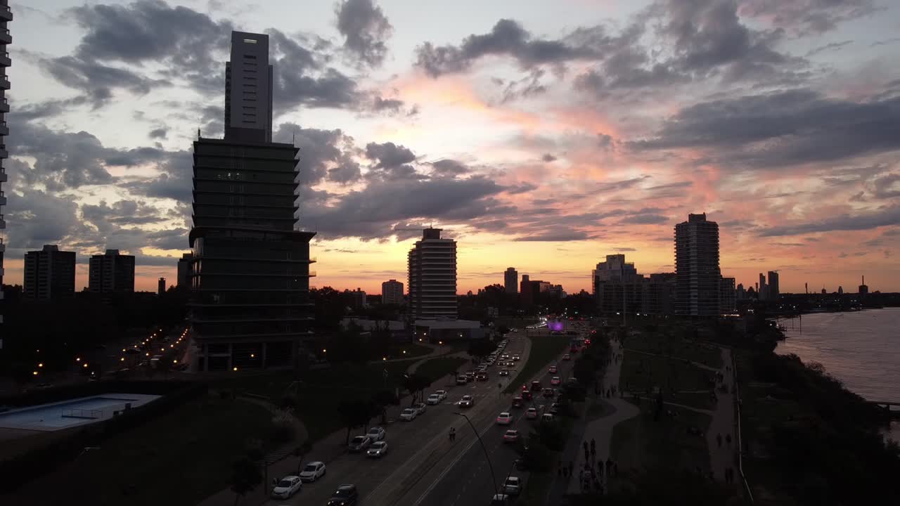 carretera llena de coches en una tarde de otoño a lo largo del río con los edificios de oficinas al fondo