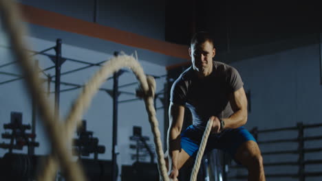 man working out with battle ropes in a gym