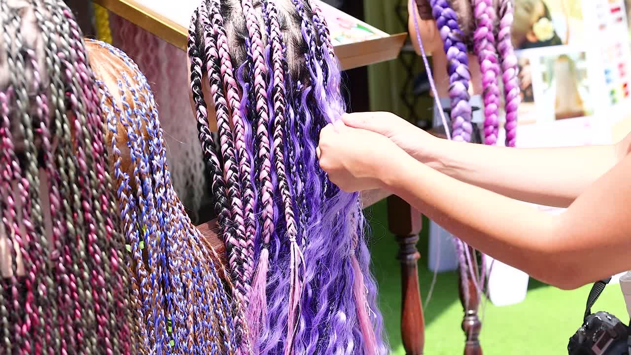 Vibrant braids in various colors are displayed in a Phuket market. Bright lighting highlights the intricate textures and hues