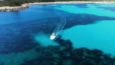 Dron-Cinematográfico-Panorámico-Alrededor-De-Un-Barco-De-Lujo-Que-Flota-En-Un-Sistema-De-Arrecifes-Poco-Profundos-Frente-A-La-Costa-De-Menorca,-España