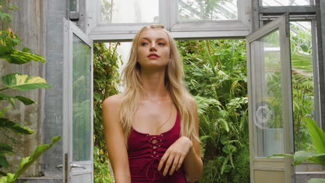 Fit-swimwear-model-walking-through-a-botanical-garden,-wearing-a-red-bikini-one-piece