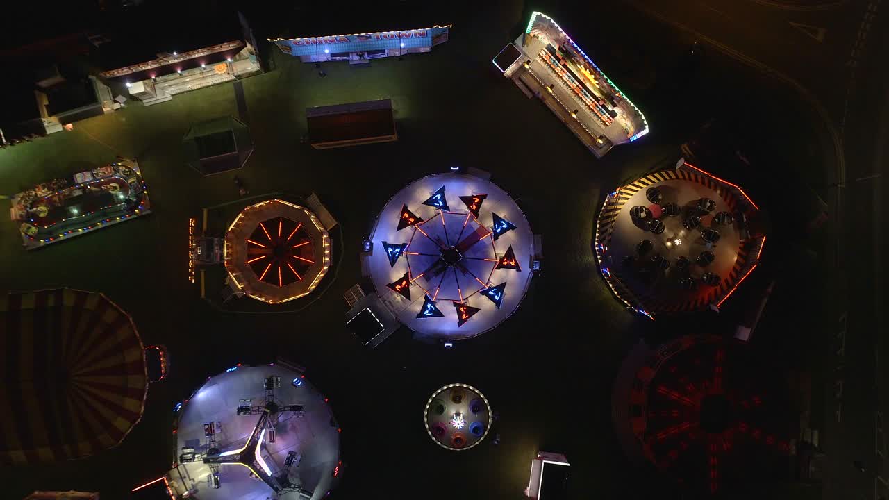 Experience the vibrant energy of an amusement park at night with this breathtaking aerial view of flashing fairground rides. Captured from above, showcases the dazzling lights and dynamic movements.
