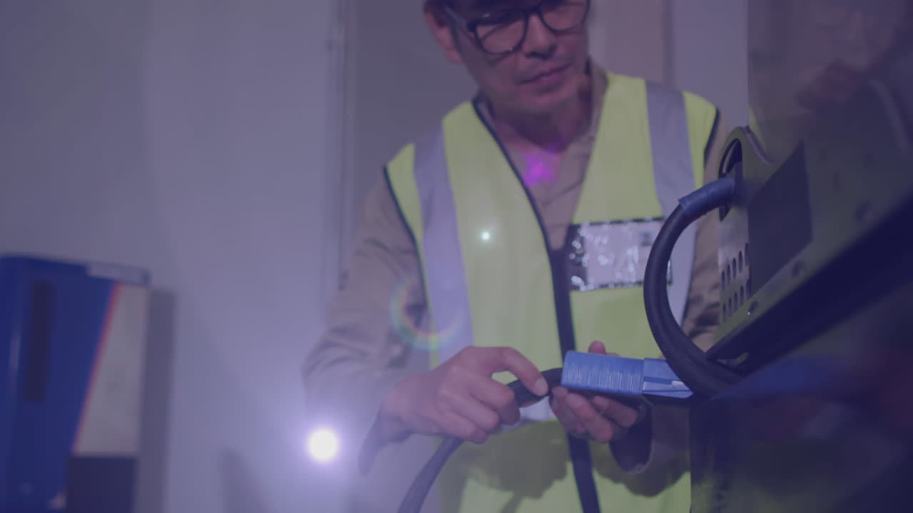 Animation of glowing light over asian man working in warehouse