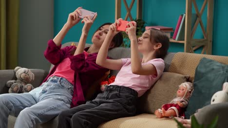 mother and daughter using smartphones on couch