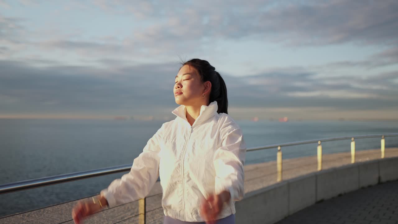 日の出の海辺でストレッチする若いアジア人女性