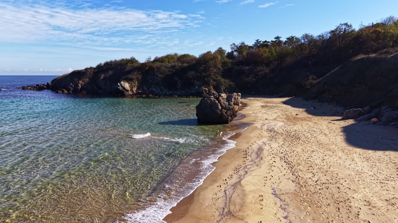 Spiaggia incontaminata con onde delicate e cielo blu intenso durante una giornata di sole lungo la serena costa