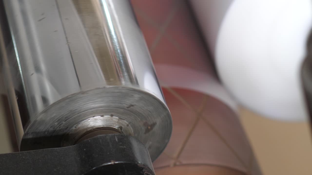 플라스틱 셀로판 가방을 늘리는 금속 롤러의 클로즈업 보기