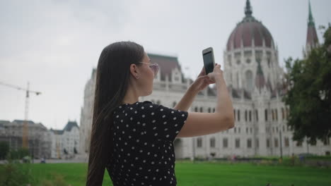 mujer tomando una foto del edificio del parlamento húngaro