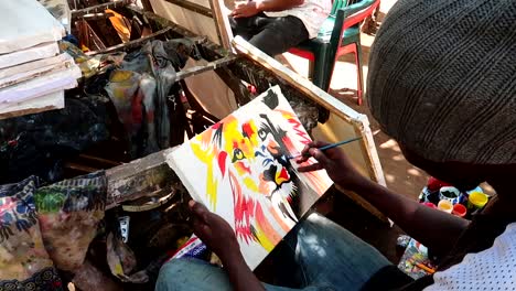 close-up of tinga tinga tribe painter man painting a colorful picture of a lion