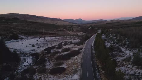 Kurvenreiche-Straße-In-Skye-In-Der-Dämmerung-Mit-Schneeflecken-Und-Ruhiger-Landschaft