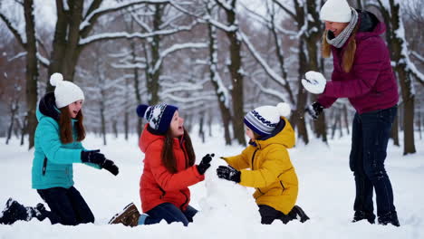 family and kids playing in the snow and having a snowball fight