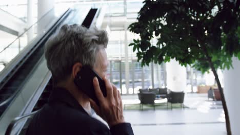 Businesswoman-talking-on-mobile-phone-in-the-lobby-at-office-4k