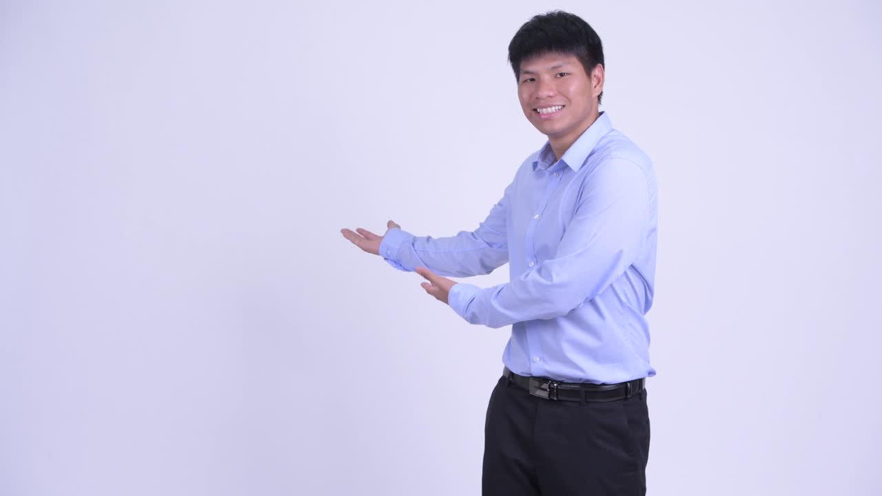 행복한 젊은 아시아 사업가 뒤에서 무언가를 보여주고