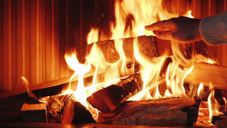 a man puts oak firewood in a fireplace insert raises the glass guillotine type puts the log in the f