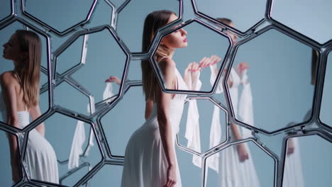 woman in white dress reflected in hexagonal mirror structure