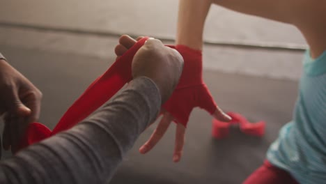 video of hands of diverse woman and man tying tapes, preparing for box training at gym