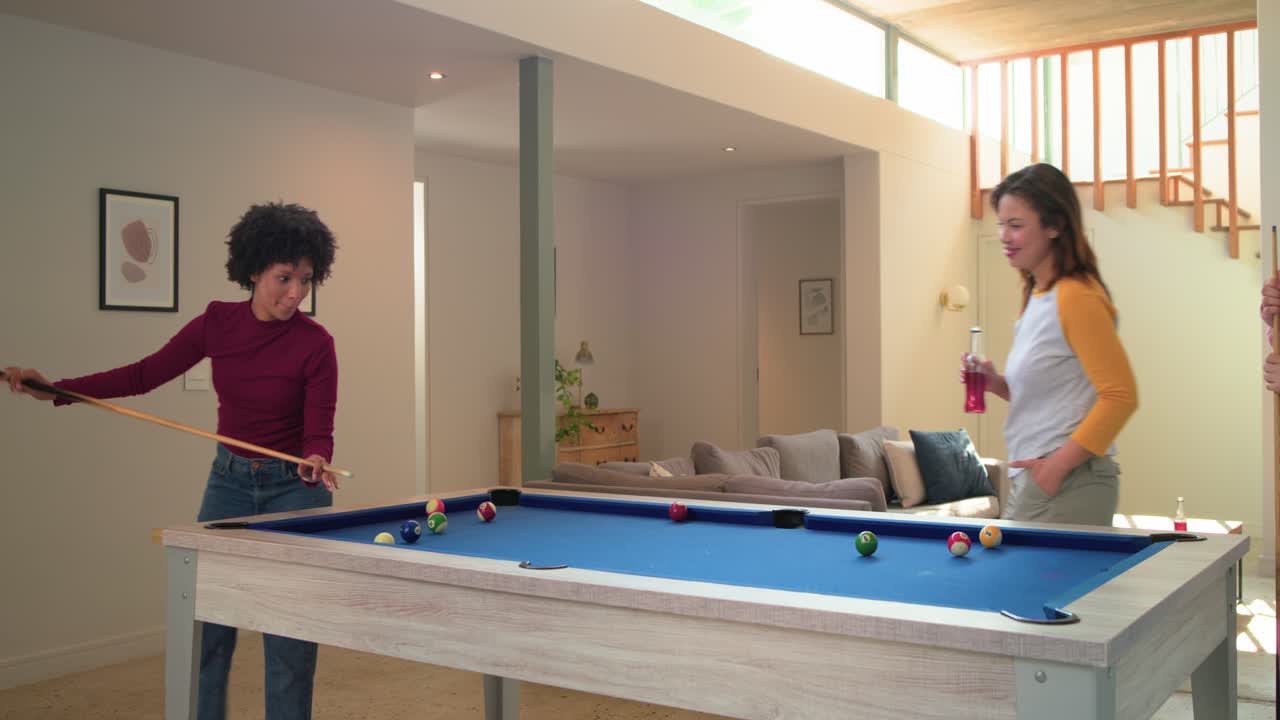 Missing shot sparking laughter while three female friends trading cues at home on pool table