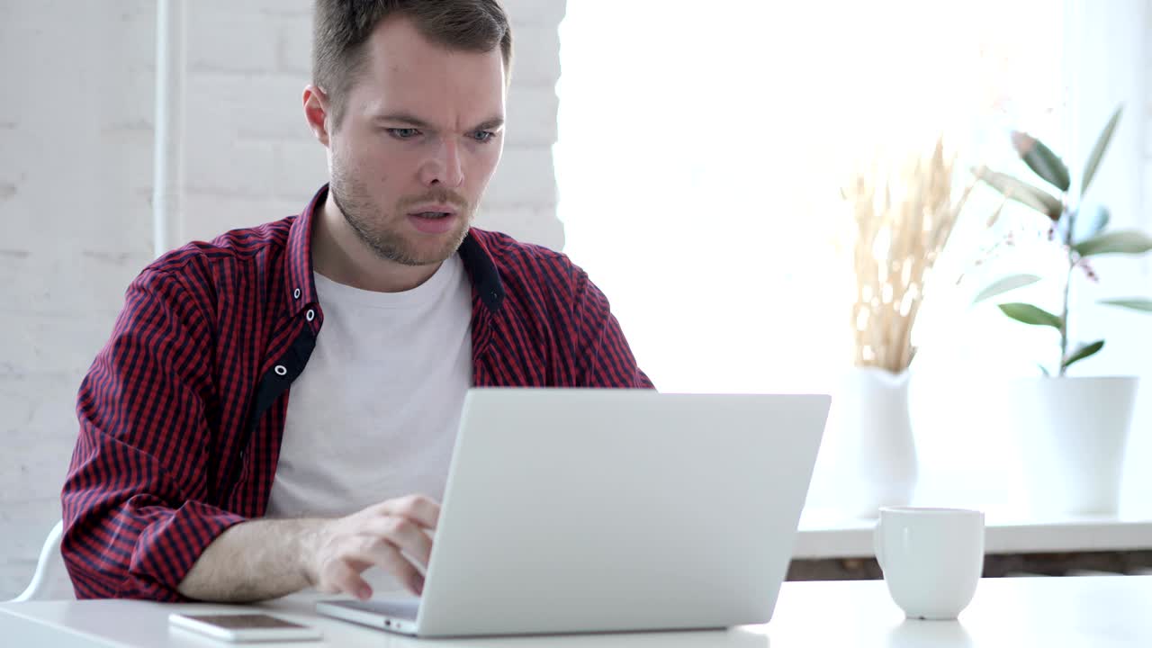 joven en estado de shock mientras trabajaba en la computadora portátil