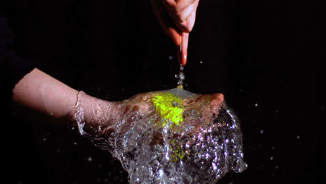 man bursting green water balloon