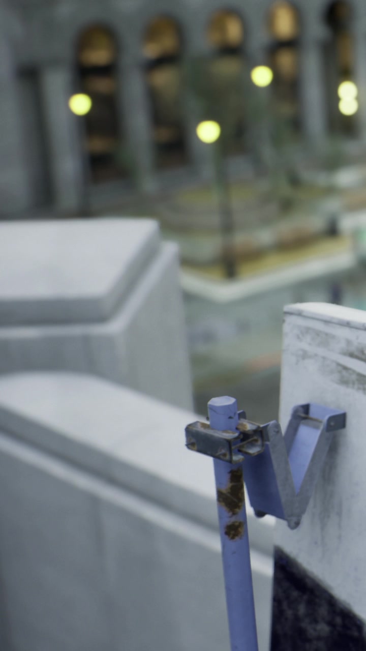 Metal hook attached to wall in urban setting with blurred background details