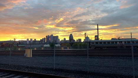 una tranquila puesta de sol dorada, roja y azul sobre el horizonte de montreal y una línea de ferrocarril vacía