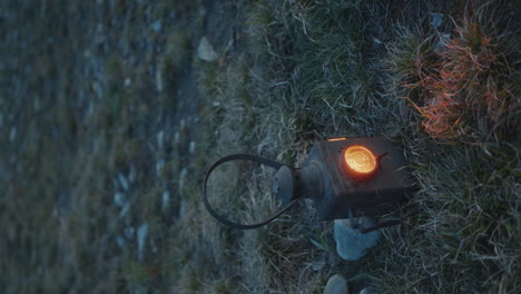 antique lantern with glowing light placed on grass at twilight