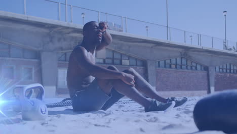 animation of glowing lights over african american man training in sun taking a break on beach