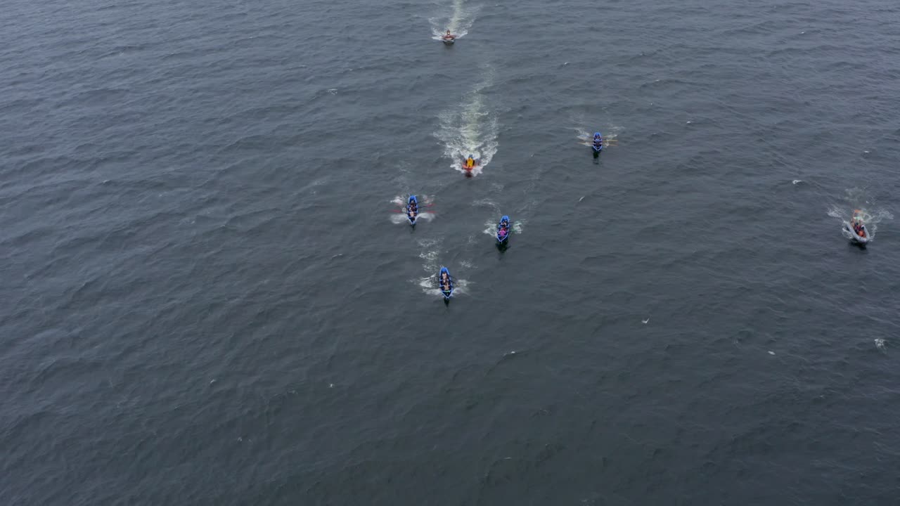 Frontal aerial view of currach racing boats in galway paddling towards open ocean